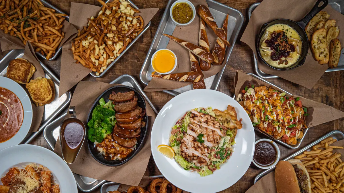 An overhead spread of Perfect SZN dishes including wings, poutine, nachos and burgers