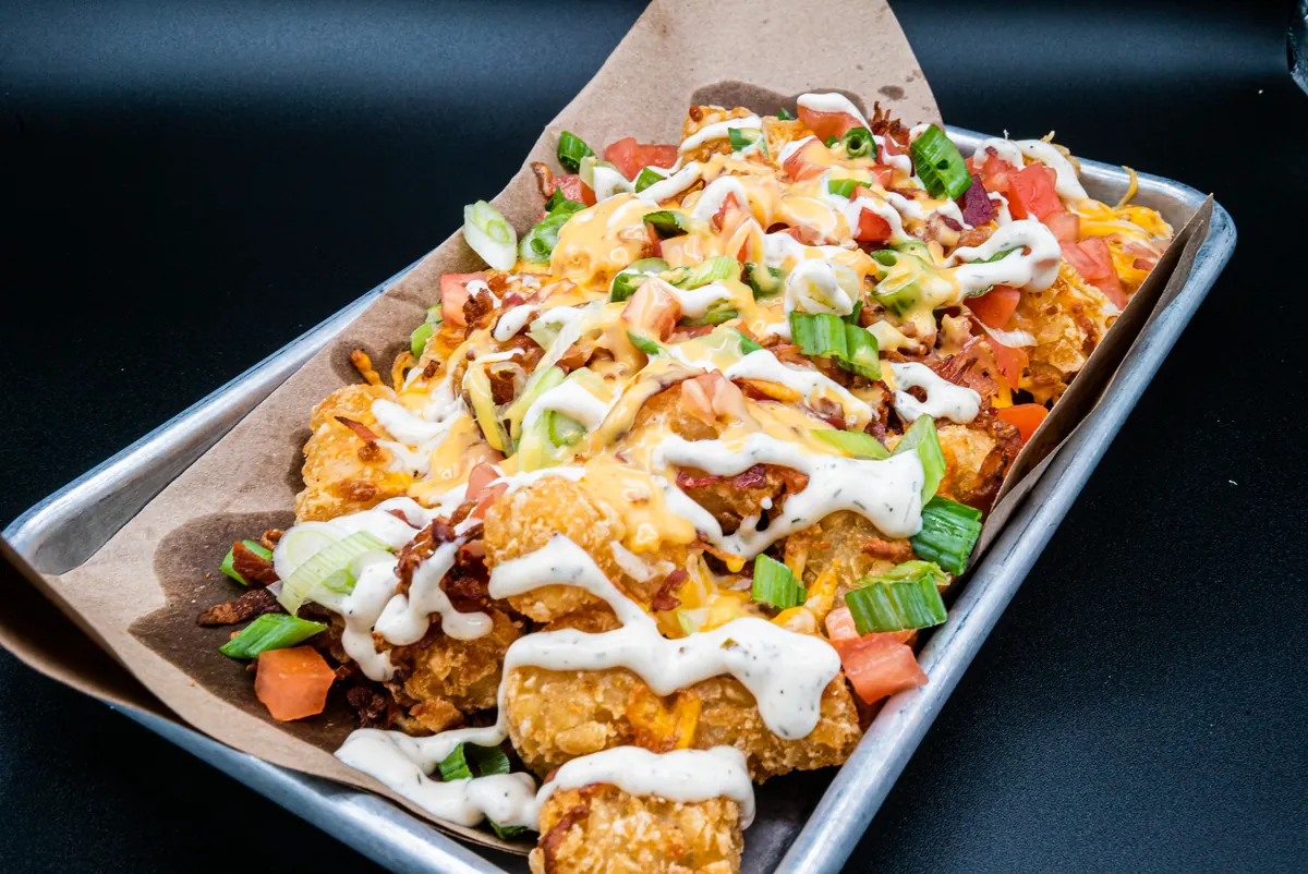 Loaded Perfect SZN nachos topped with cheese, scallions and sour cream